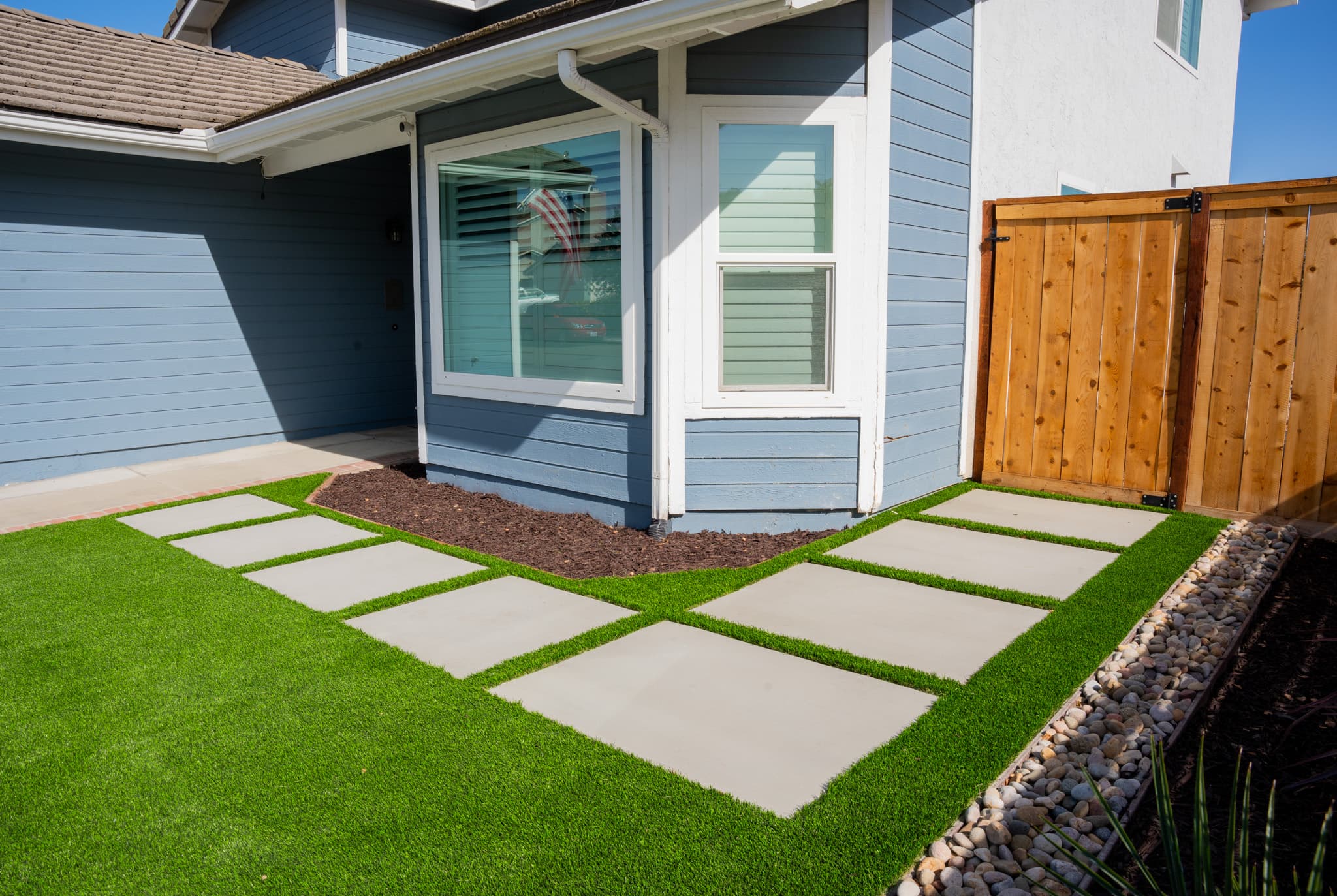 Front yard renovation with custom horizontal slat fence and drought-tolerant plants.