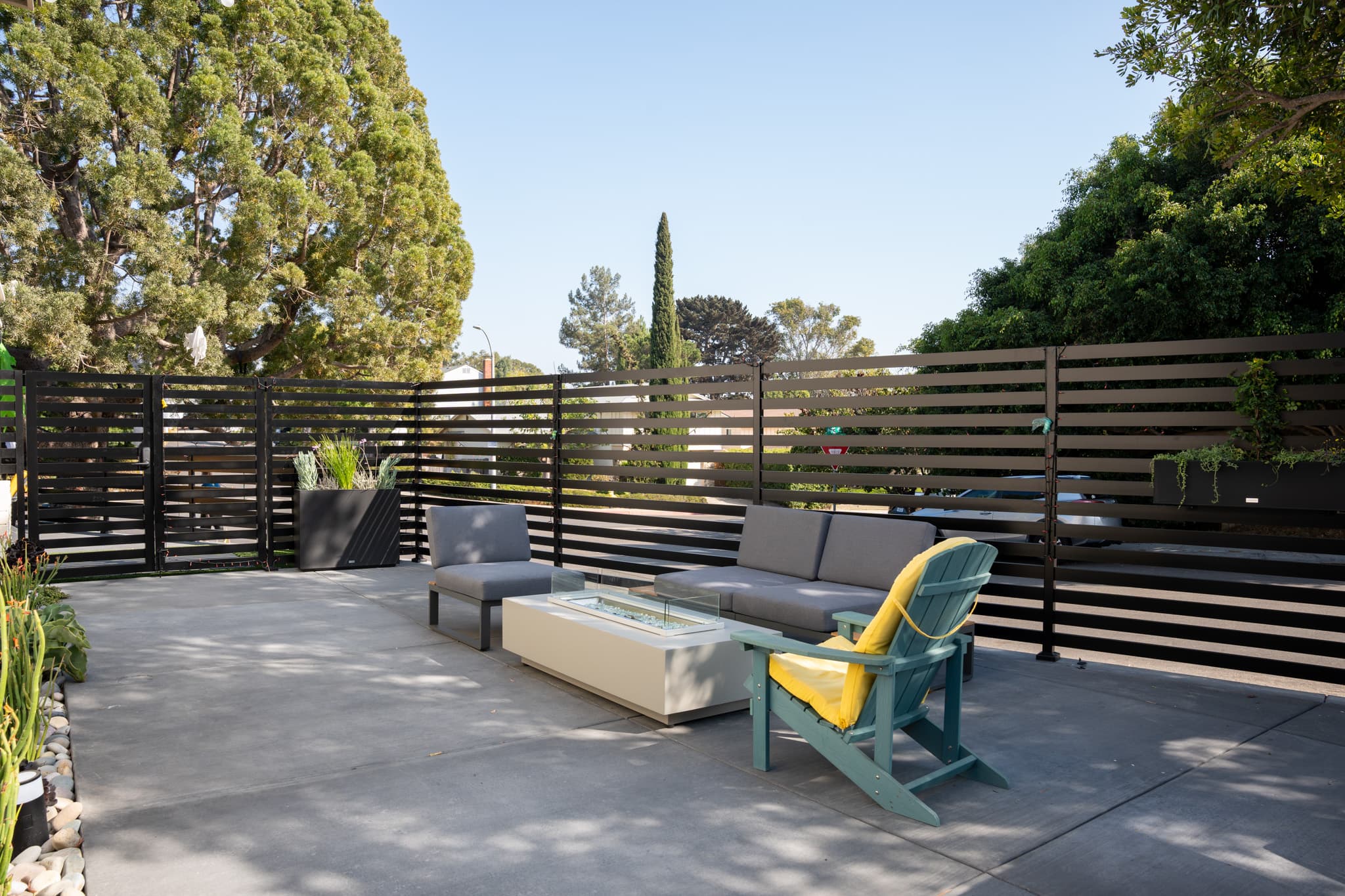 Custom concrete patio with string lights, fire pit, and sleek metal fencing