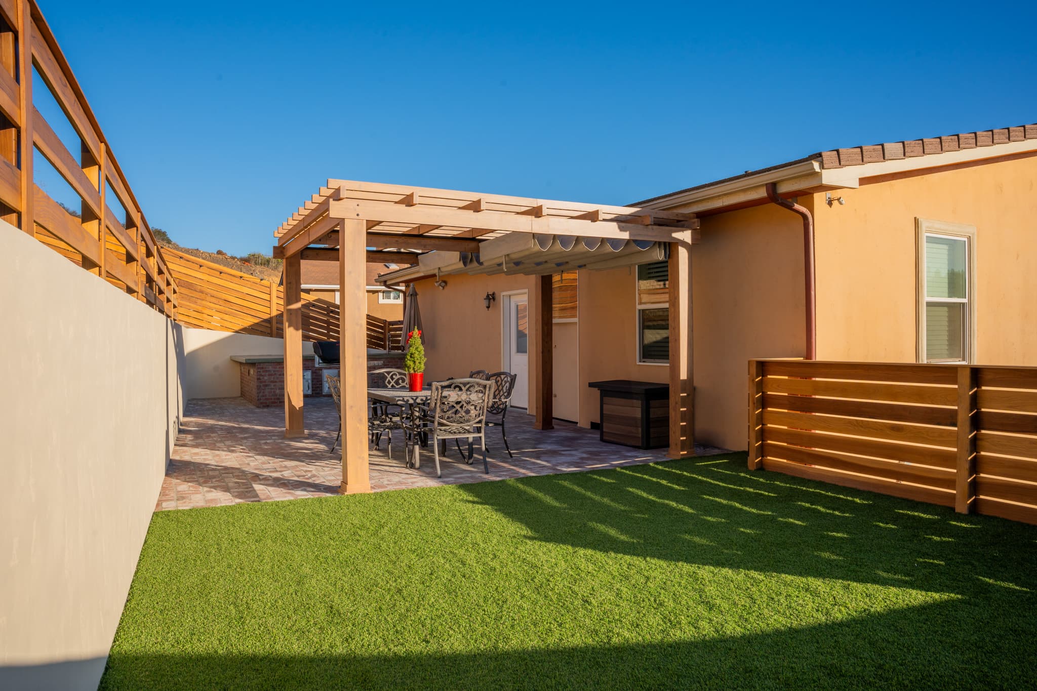 A beautifully designed backyard featuring tiered retaining walls, artificial turf, custom wooden fencing, and outdoor lighting.