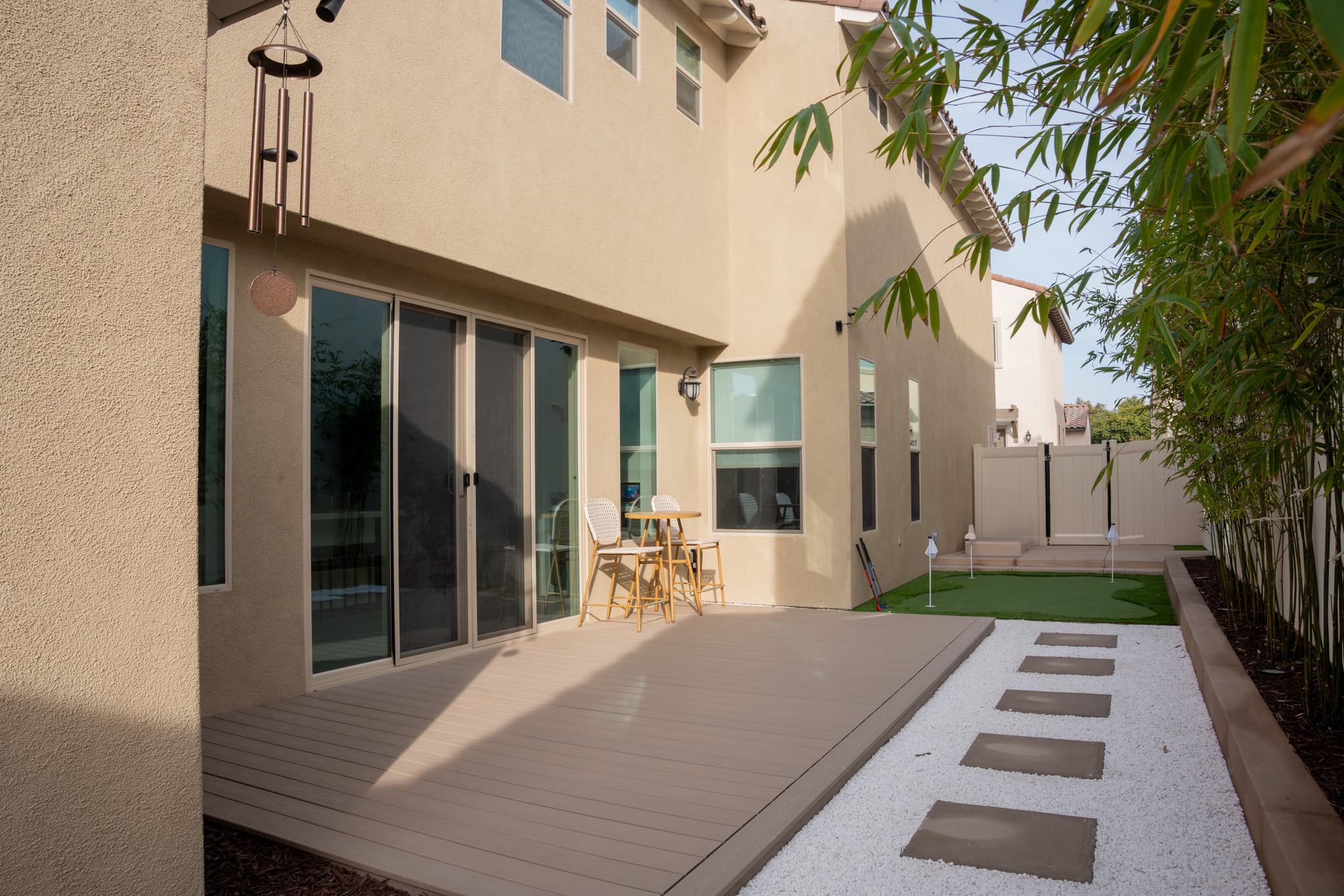 Putting green and backyard retreat with artificial turf, stepping stones, and elegant hardscaping.