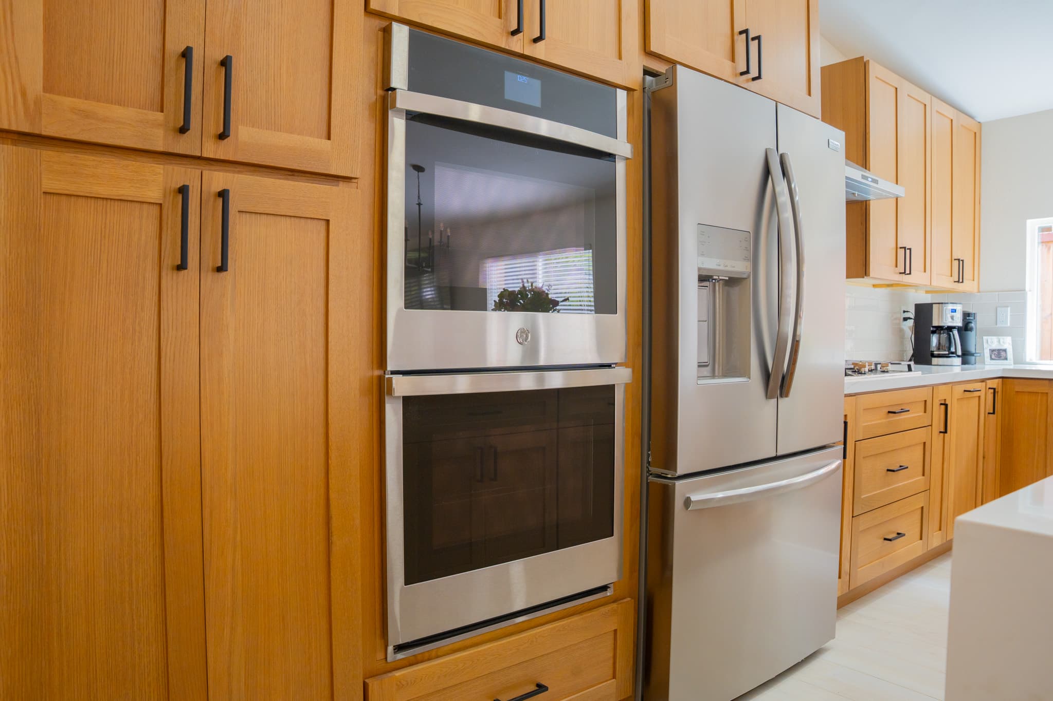 Kitchen remodel featuring floor-to-ceiling cabinets with black hardware and stainless steel oven.