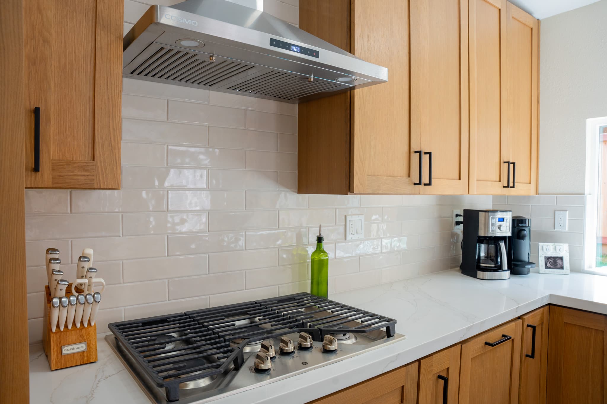 Modern kitchen oven area with double stainless steel oven, custom wood cabinetry, and black hardware.
